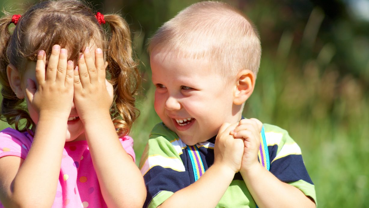 Two funny kids are playing, covering his face with his hands